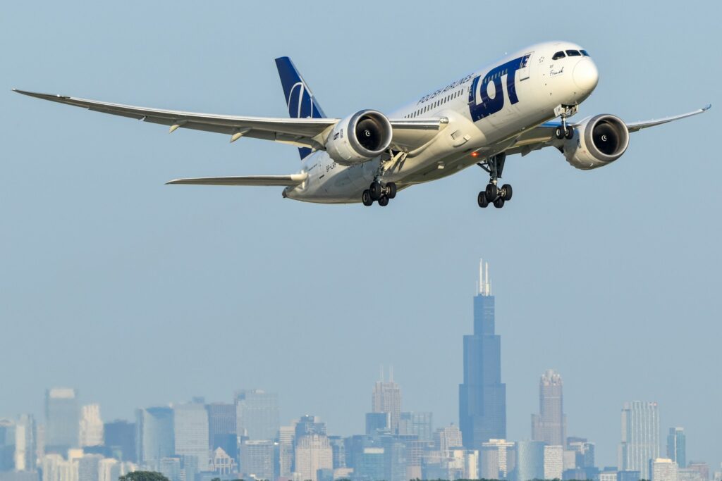 A large jetliner flying over a city skyline